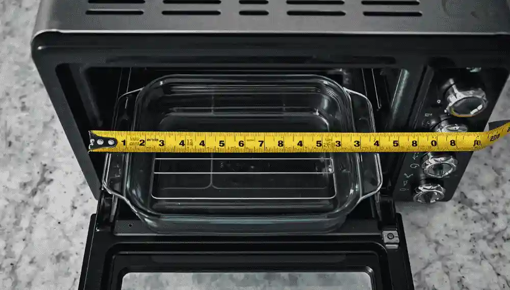 Measuring a 9x13 casserole dish against a small toaster oven to check size compatibility